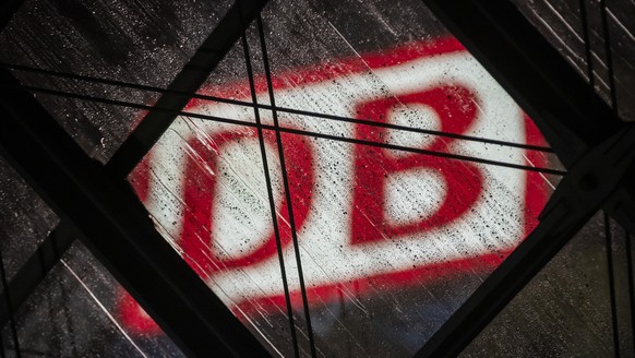 ARCHIV - 24.01.2024, Berlin: Das DB-Logo hinter dem regennassen Glasdach des Berliner Hauptbahnhofs. (zu dpa:
