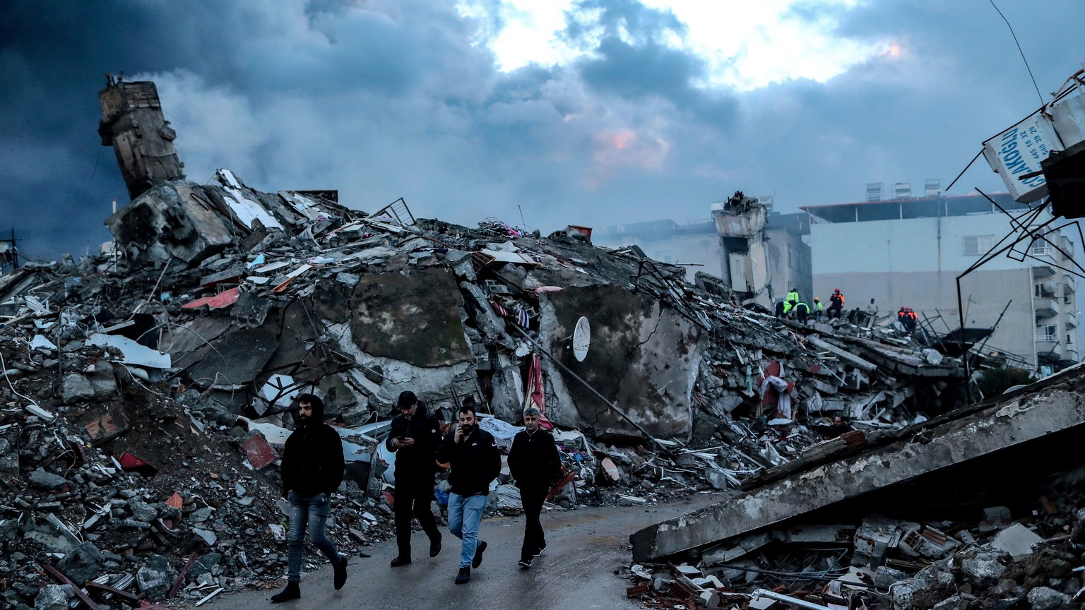 epa10452169 People walk on the site of a collapsed building after an earthquake in Iskenderun, Hatay district, Turkey, February 7, 2023. More than 4,000 people were killed and thousands more in ...