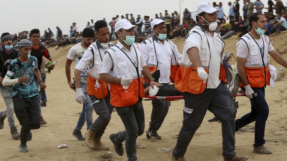 Palestinian medics evacuate a wounded youth during a protest at the Gaza Strip&#039;s border with Israel, east of Khan Younis, Gaza Strip, Friday, May 4, 2018. (AP Photo/Adel Hana)