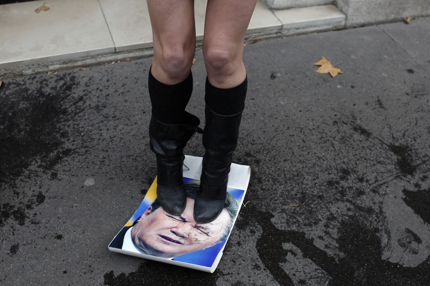 ARCHIV - ZUM 5. JAHRESTAG DER EUROMAIDAN, DER BUERGERPROTESTE IN DER UKRAINE, STELLEN WIR IHNEN FOLGENDES THEMENBILD ZUR VERFUEGUNG -A Femen activist stands on a poster of Ukrainian President Viktor Y ...