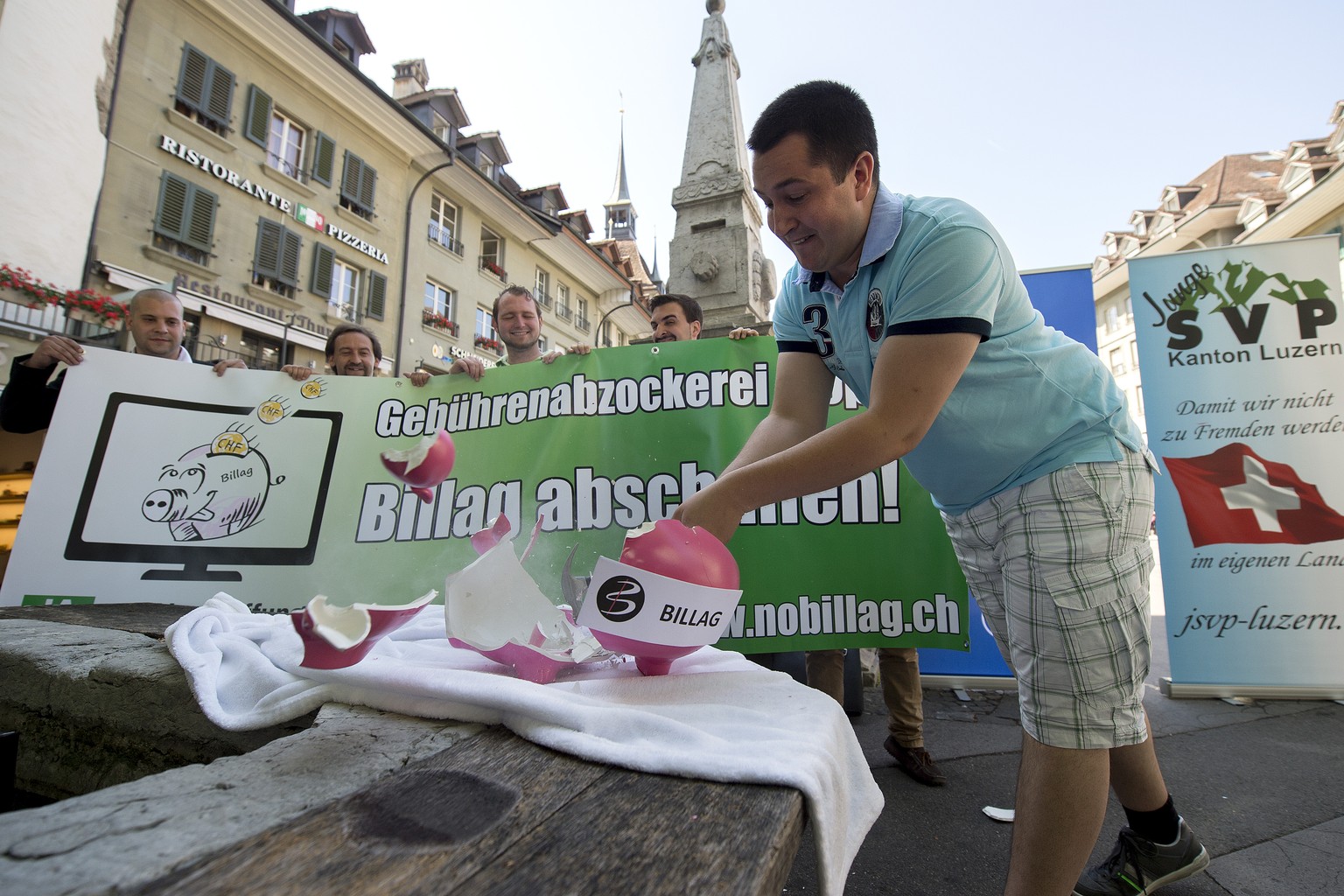 Das Billag-Sparschwein soll geschlachtet werden: Anian Liebrand, Präsident der Jungen SVP, holt schon einmal zum symbolischen Akt aus.