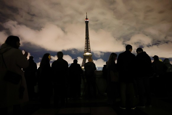 epaselect epa11981998 People look on the Eiffel Tower with lights switched off to mark Earth Hour 2025 in Paris, France, 22 March 2025. Earth Hour is held annually as a symbol of commitment to the pla ...