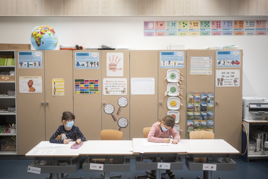 Zwei Schuelerinnen tragen Hygienemasken, um sich und andere gegen eine Uebertragung des Coronavirus zu schuetzen, in einem Schulzimmer der Schule Pfingstweid in Zuerich, aufgenommen am Dienstag, 11. J ...