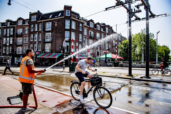 epa07739596 A city worker sprays water over the Wiegbrug in Amsterdam, the Netherlands, 25 July 2019. The Royal Dutch Meteorology Institute (KNMI) has issued an official warning due to the warm weathe ...