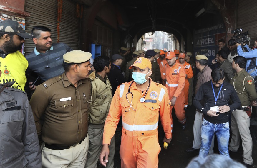 Medical officers and policemen come out from the site of a fire in an alleyway, tangled in electrical wire and too narrow for vehicles to access, in New Delhi, India, Sunday, Dec. 8, 2019. Dozens of p ...