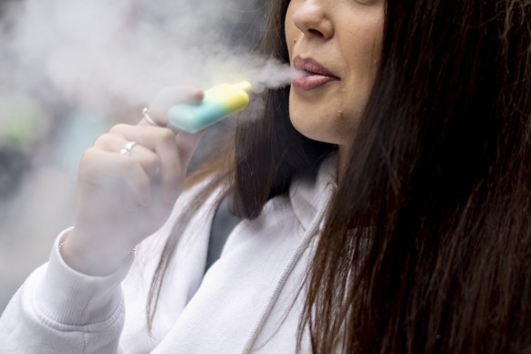 epa10663273 A person uses a single-use vaping product in London, Britain, 30 May 2023. The UK government has announced it is cracking down on retailers providing free vape samples to children. The gov ...
