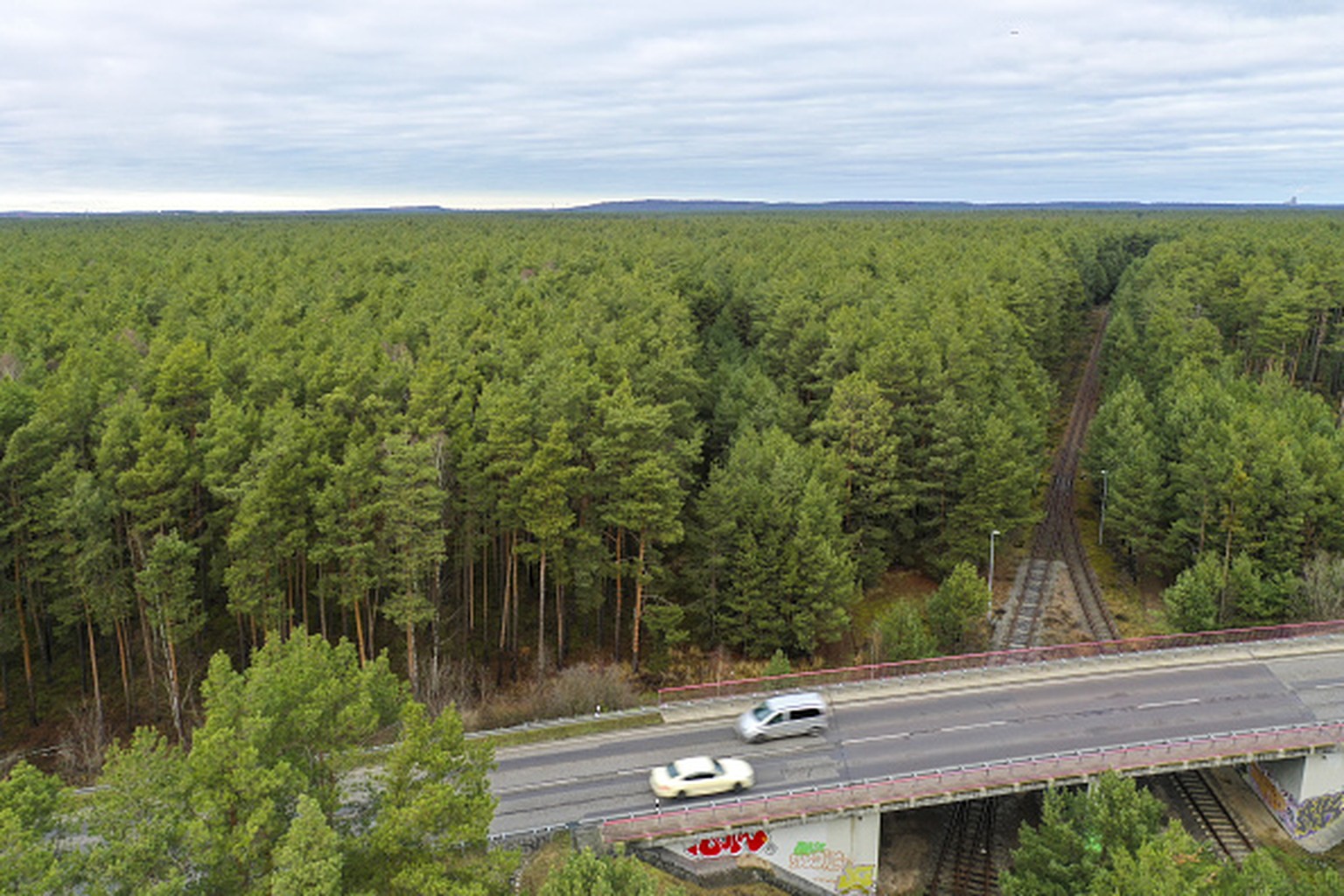 Traffic passes along a road bridge over railway lines in a forested area of the proposed location for a Tesla Inc. Gigafactory, in this aerial photograph taken above Gruenheide, Germany, on Saturday,  ...