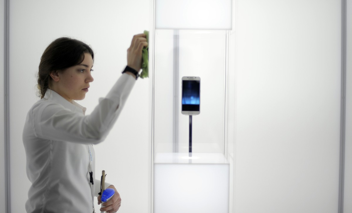 A woman cleans a glass cabinet containing the new Galaxy S6 smartphone during the Mobile World Congress, the world's largest mobile phone trade show in Barcelona, Spain, Tuesday, March 3, 2015. ( ...