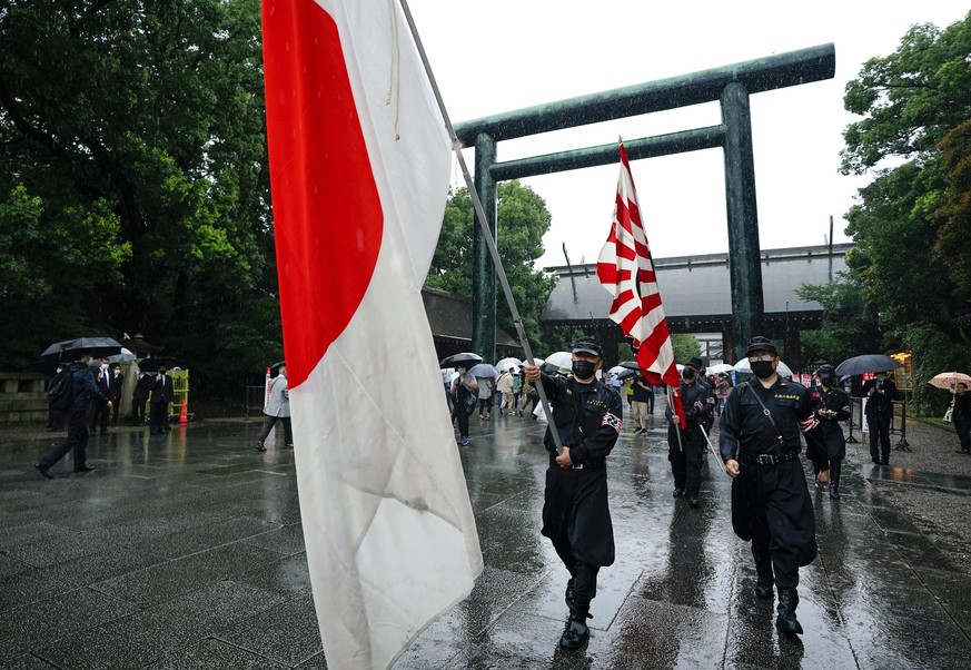 epaselect epa09414596 People holding a national flag and their group flags leave Yasukuni Shrine after paying tribute to the war dead on the 76th anniversary of the end of World War II, in Tokyo, Japa ...