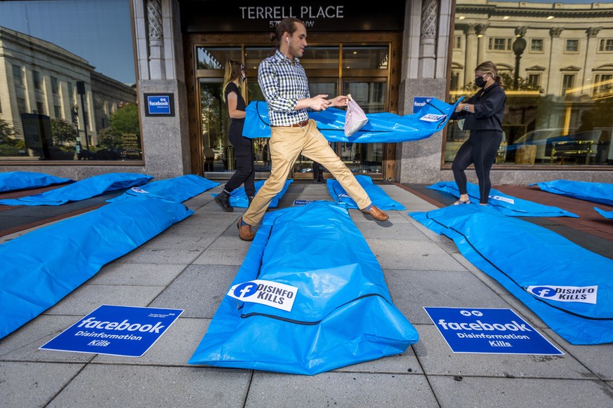 IMAGES DISTRIBUTED FOR ALL THE CITIZENS LTD - A pedestrian steps over body bag props at Washington, DC Facebook headquarters as activists lay body bags and call for Facebook to stop disinformation tha ...