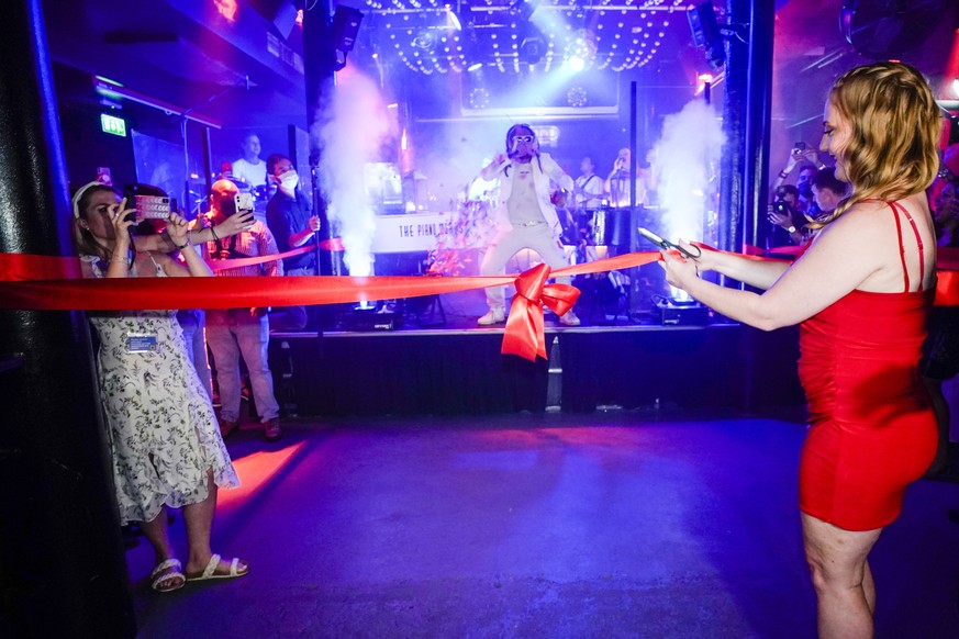 A woman cuts the ribbon on the dance floor of The Piano Works in Farringdon, in London, Monday, July 19, 2021. Thousands of young people plan to dance the night away at &#039;Freedom Day&#039; parties ...