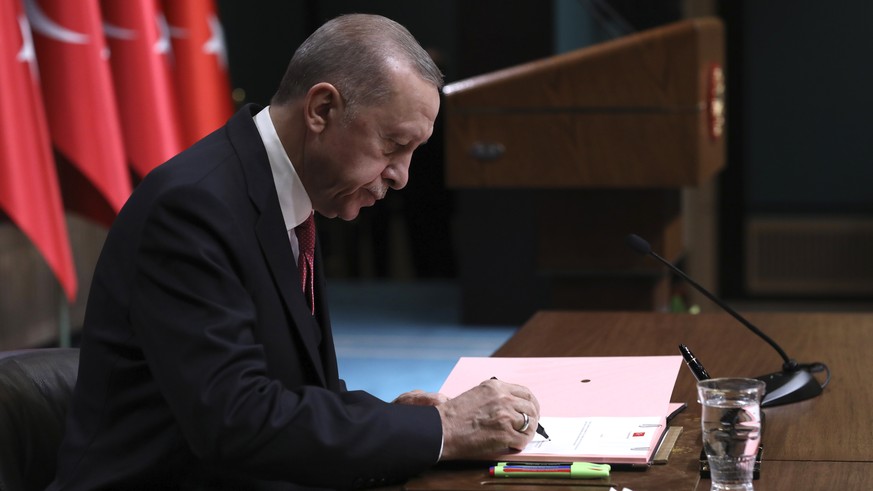 Turkey&#039;s President Recep Tayyip Erdogan puts his signature on a decision confirming the election date, in Ankara, Turkey, Friday, March 10, 2023. Erdogan, who is seeking to extend his two decades ...