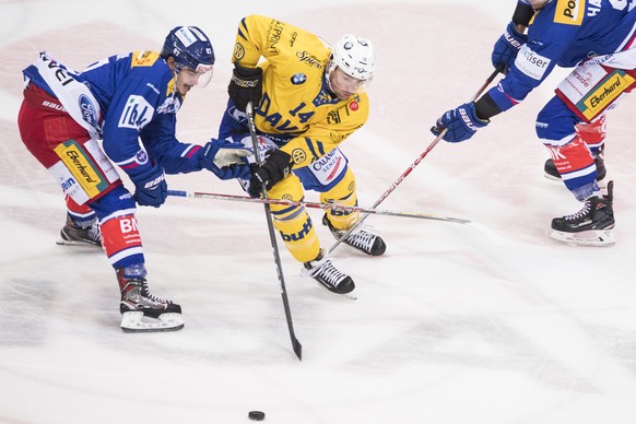 Davoser Broc Little, Mitte, spielt um den Puck gegen Marc Marchon, links, von Kloten waehrend dem Eishockey-Meisterschaftsspiel der National League zwischen den EHC Kloten und dem HC Davos am Freitag, ...