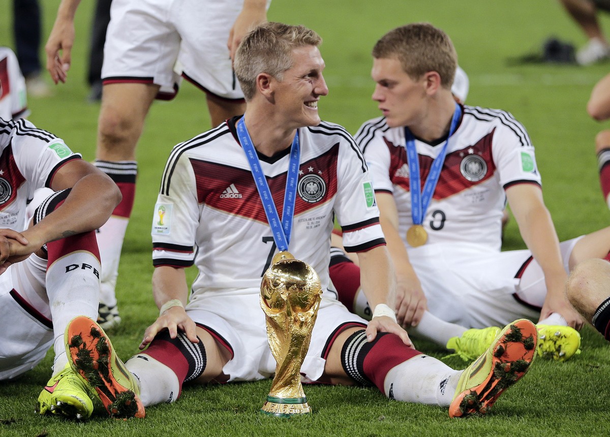Germany's Bastian Schweinsteiger sits on the pitch with the trophy after the World Cup final soccer match between Germany and Argentina at the Maracana Stadium in Rio de Janeiro, Brazil, Sunday,  ...