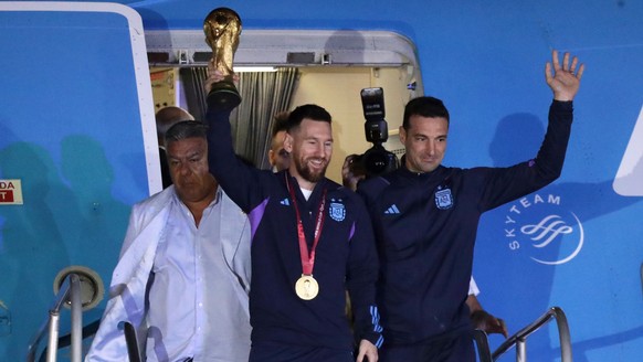 epa10374424 Lionel Messi (C) of the Argentina national soccer team descends a plane with the trophy of Qatar 2022 World Cup accompanied by head coach Lionel Scaloni (R), upon ther arrival to the Inter ...