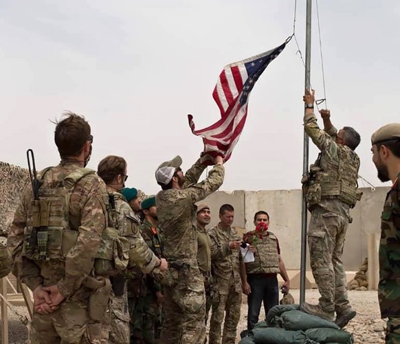 A U.S. flag is lowered as American and Afghan soldiers attend a handover ceremony from the U.S. Army to the Afghan National Army, at Camp Anthonic, in Helmand province, southern Afghanistan, Sunday, M ...