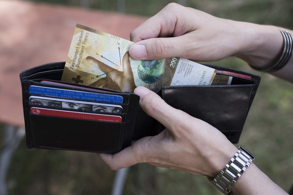 A person takes a 200 Swiss franc bill out of a wallet, pictured in Zurich, Switzerland, on August 23, 2018. (KEYSTONE/Christian Beutler)

Eine Person entnimmt eine 200-Franken-Banknote aus einem Porte ...