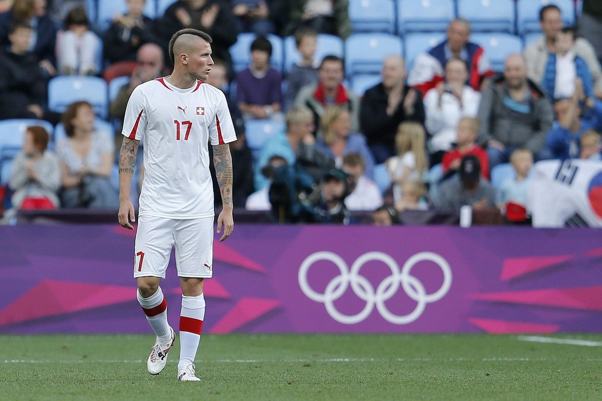 Switzerland's Michel Morganella looks on while Korea's players celebrate after scoring the 1-0 during the Group B preliminary match between Switzerland and South Korea at the City of Coventr ...