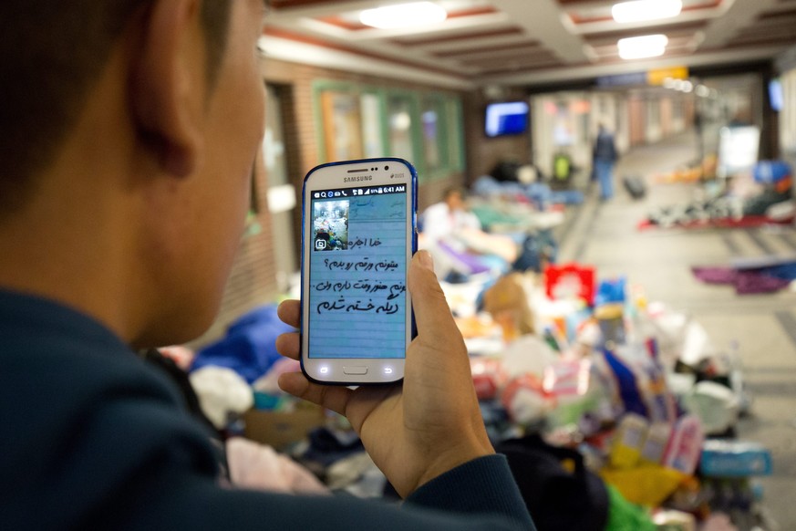 epa04923217 Mogfaba, a 16-year-old refugee from Afghanistan, uses a mobile phone at the train station in Flensburg, Germany, 10 September 2015. A first train with refugees left in the morning from Fle ...