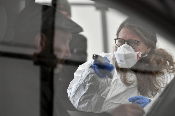 FILE - In this on Tuesday, March 10, 2020 file photo, a member of the medical staff measures the temperature of a traveller at a autobahn park place near Gries am Brenner, Austria near the border cros ...