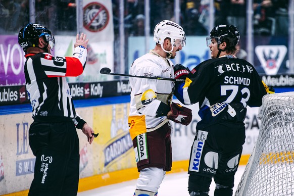L?attaquant genevois Noah Rod, gauche, lutte avec l'attaquant fribourgeois Sandro Schmid, droite, sous les yeux de l?arbitre Stefan Huerlimann, gauche, lors du match du championnat suisse de hockey su ...