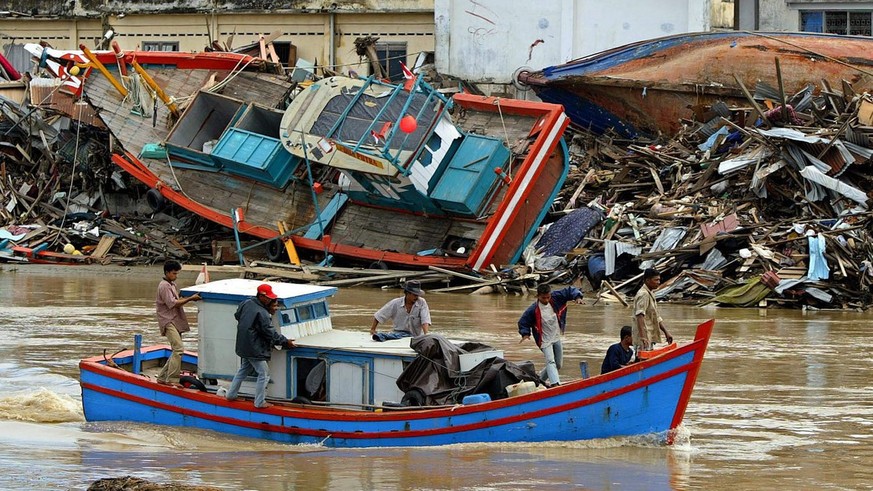 A traditional fisherman boat moves past a stranded boat hit by the 26 December 2004 tsunami in Banda Aceh, Sumatera, Indonesia on Tuesday 18 January 2005. Indonesia was the hardest hit country by the  ...