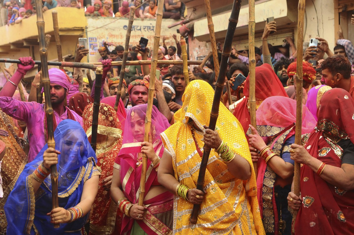 Indian women from Barsana village beat villagers from Nandgoan with wooden sticks as they tease them during Lathmar holi festival celebrations at the legendary hometown of Radha, consort of Hindu God  ...