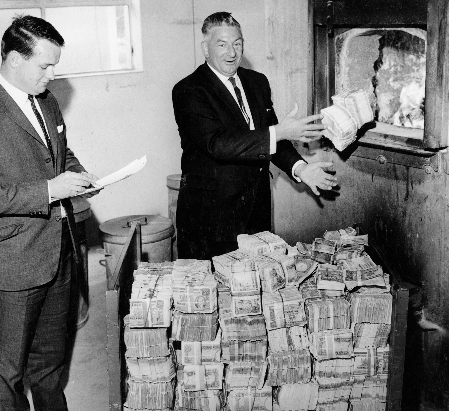 Stacks of pound notes are fed into the furnace by the Reserve Bank&#039;s Eric Vallance after the change to decimal currency in 1967.
Dominion Post collection, ALEXANDER TURNBULL LIBRARY Ref: EP-Econo ...