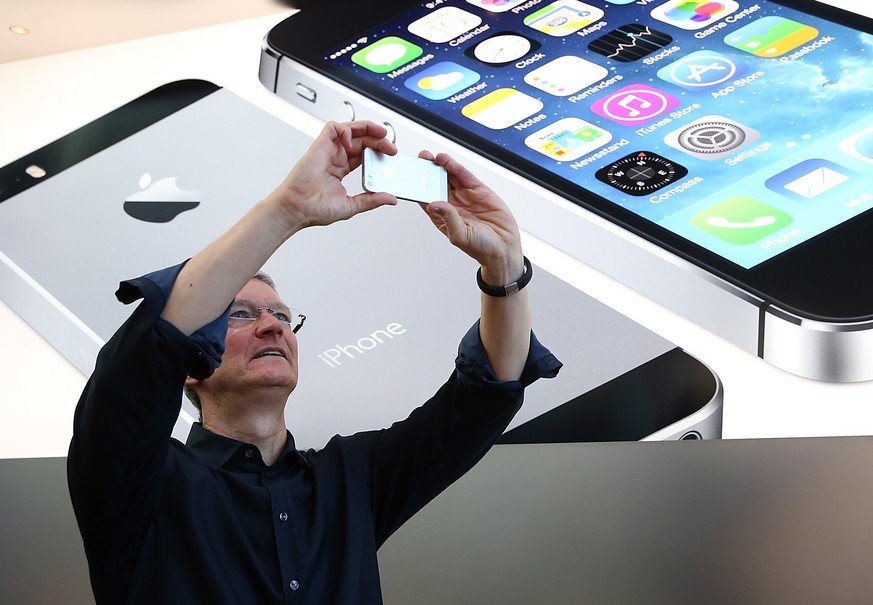 PALO ALTO, CA - SEPTEMBER 20: Apple CEO Tim Cook uses an iPhone to take a picture of customers waiting in front of an Apple store to purchase the new iPhones on September 20, 2013 in Palo Alto, Califo ...