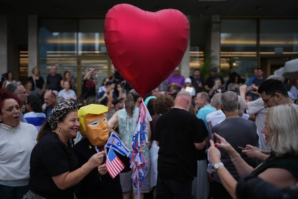 A person wears a mask depicting U.S. President Donald Trump as relatives and supporters of Israeli hostages held by Hamas in the Gaza Strip celebrate following the announcement that Israel and Hamas h ...
