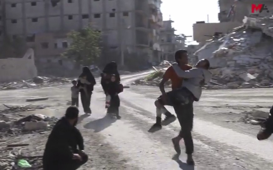 This frame grab from a video provided on Friday, Oct. 13, 2017 by Turkey-based Kurdish Mezopotamya agency media outlet that is consistent with independent AP reporting, shows Syrian civilians run on a ...