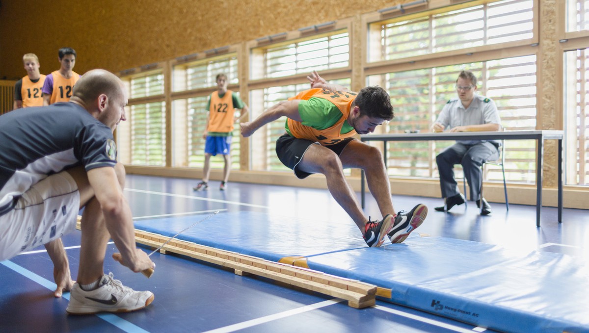 During the sports exam, a young man does the standing long jump, where he jumps from the gym floor onto a mat and where the distance between the jump line and the body's rearmost point of contact ...