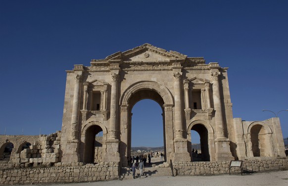 FILE - In this Nov. 13, 2015, file photo, tourists pass through the Arch of Hadrian, built during the Roman Empire, and the South Gate of the well preserved Ancient Roman city of Gerasa, in the city o ...