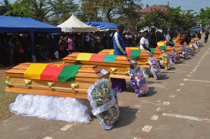 epa11030093 Relatives stand next to the caskets of the victims of an attack in Egbekaw, Mamfe district in the Southwest Region of Cameroon, 14 December 2023. Before dawn on 06 November 2023, Anglophon ...