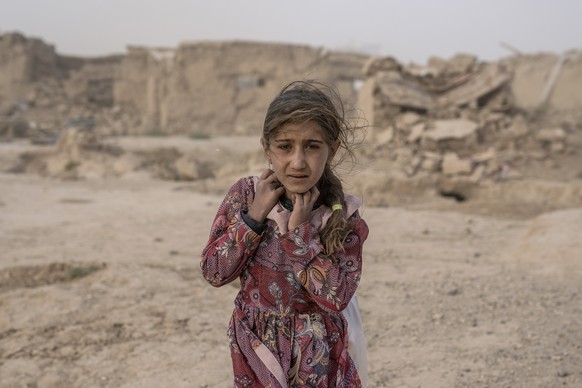 FILE - An Afghan girl carries donated aid to her tent, while she is scared from the fierce sandstorm, after an earthquake in Zenda Jan district in Herat province, western of Afghanistan, Oct. 12, 2023 ...