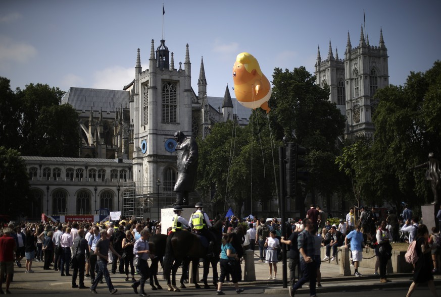 A six-meter high cartoon baby blimp of U.S. President Donald Trump hovers next to the statue of former British Prime Minister Winston Churchill, as it is flown as a protest against his visit, in Parli ...