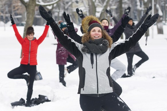 Melissa Ciampanelli, front, participates in an outdoor yoga session at a city park in Montreal, Saturday, Feb. 10, 2018. (Graham Hughes/The Canadian Press via AP)