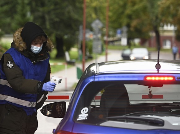 ARCHIV - Eine Mitarbeiterin misst am Eingang zum Universittsklinikum TrencÌn, Slowakei, die Krpertemperatur einer Frau im Auto. Foto: Radovan Stoklasa/TASR/dpa