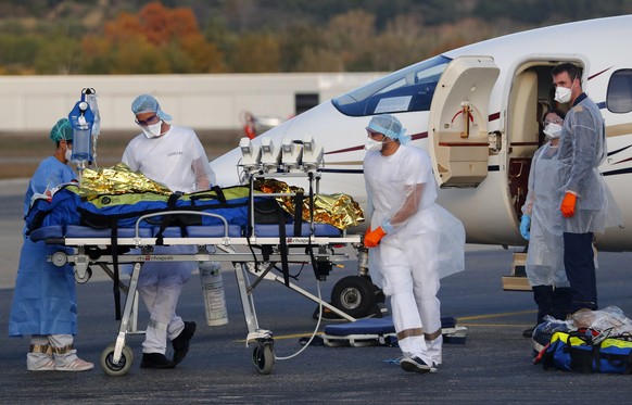 epa08798524 Hospital medical staff load a patient with the Covid-19 disease into a plane for evacuation at the Avignon's airport, France, 04 November 2020. France is in the midst of a second wave of the COVID-19 coronavirus pandemic recording 3,900 patients now hospitalized in intensive care units (ICU).  EPA/GUILLAUME HORCAJUELO