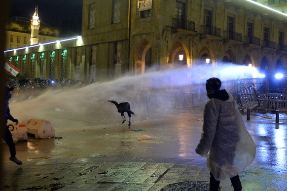 epa08142010 Lebanese riot police sprays water at protesters during continuous anti-government protests outside of the Lebanese Parliament building in downtown Beirut, Lebanon, 19 January 2020. Police  ...