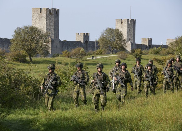 epa05539256 A squad from the Swedish Army's Skaraborg Armoured Regiment patrols outside Visby's 13th century city wall during a military maneuver in Visby, on the island of Gotland, 14 Septe ...