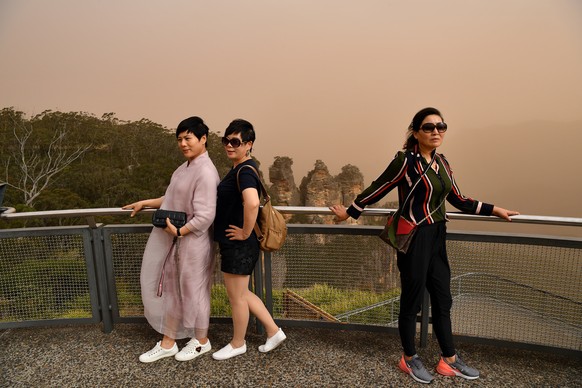 epa07990042 Tourists stand at the Three Sisters lookout in Katoomba in Sydney, New South Wales, Australia, 12 November 2019. At least 60 fires are burning across New South Wales, with a fire front of  ...