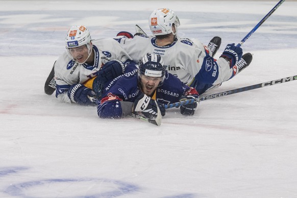 Yannick Zehnder, vorne, von Zug im Spiel gegen Justin Sigrist, links, und Patrick Geering, rechts, vom ZSC beim Eishockey Meisterschaftsspiel der National League zwischen dem EV Zug und den ZSC Lions  ...