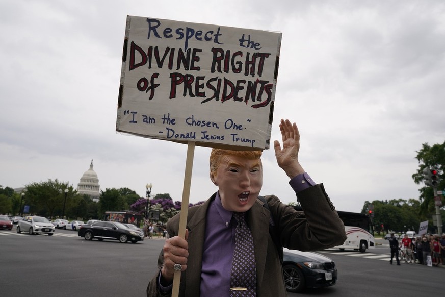 The U.S. Capitol is seen in the distance as a protester, in a Former President Donald Trump mask, holds a sign near the E. Barrett Prettyman U.S. Federal Courthouse, Thursday, Aug. 3, 2023, in Washing ...