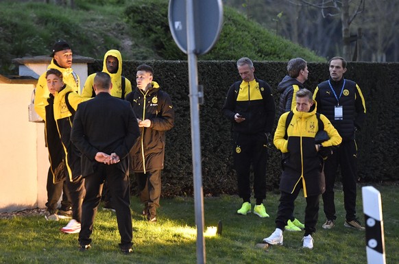 Head coach Thomas Tuchel, right, and players of Borussia Dortmund stand outside their team bus after it was damaged in an explosion before the Champions League quarterfinal soccer match between Boruss ...