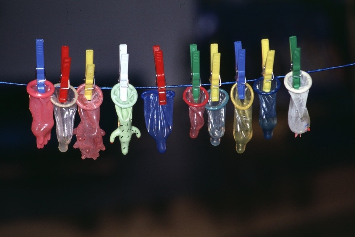 Des préservatifs colorés suspendus à une corde à linge.