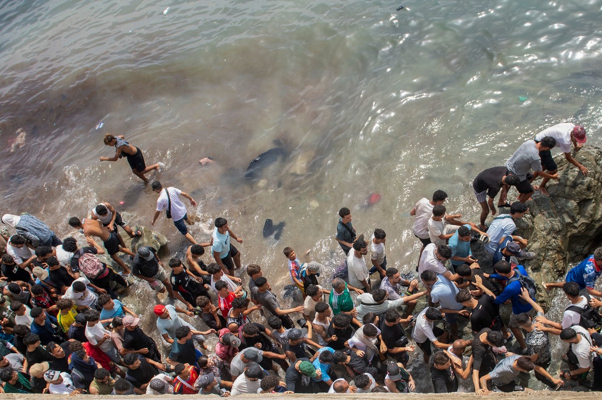 FILE - People walk on a beach as they attempt to cross from the Moroccan northern town of Fnideq to the Spanish enclave of Ceuta, July 31, 2026. (AP Photo, File)
Migration Spain Ceuta