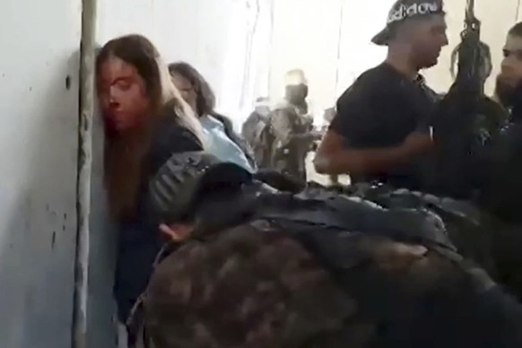 In this image taken from video provided by the Hostage Families Forum, Israeli female soldiers from the Nahal Oz military base are placed against the wall and shackled by members of Hamas after they w ...