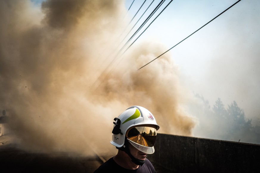 epa10064070 A cloud of smoke rises as a firefighter stands during a forest fire in Canecas, outskirts of Lisbon, Portugal, 10 July 2022. Portugal&#039;s President warned that the risk of fires will re ...