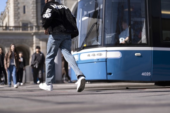 Personen zu Fuss ueberqueren die Tramgleise bei der Tramhaltestelle der VBZ Bahnhofquai / Hauptbahnhof, fotografiert am Donnerstag, 20. Maerz 2025 in Zuerich. (KEYSTONE/Gaetan Bally)